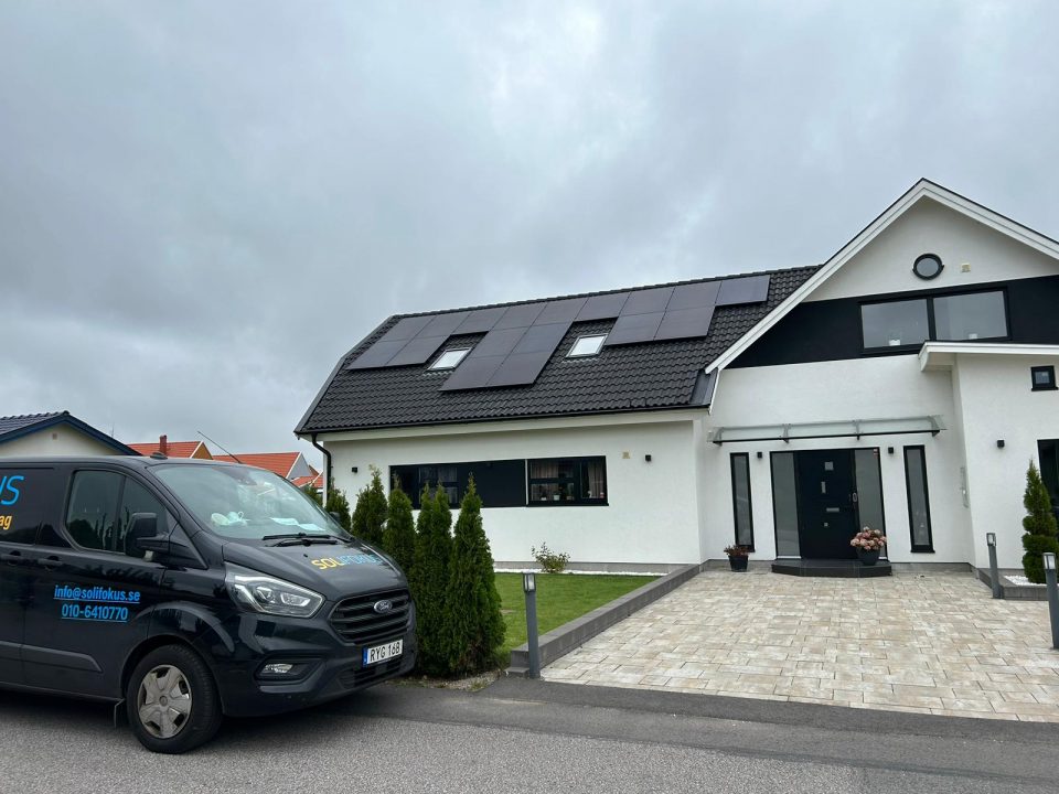 En bild av en modern villa med svart tak och solceller på. Solcellerna är diskret placerade på taket och smälter väl in i husets design. Framför villan finns en Solifokus servicebil parkerad, vilket visar att Solifokus har installerat solcellerna på detta hus. Denna bild illustrerar användningen av solenergi för att driva hemmets elförbrukning och betonar Solifokus' expertis inom solenergilösningar.