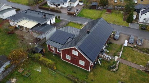 Bild på ett tak med solceller installerade av Solifokus. Bilden är tagen från en höjd och visar olika hus, trädgårdar och bilar runt omkring, vilket illustrerar hur solcellerna integreras i olika boendemiljöer och möjliggör hållbar energiproduktion.
