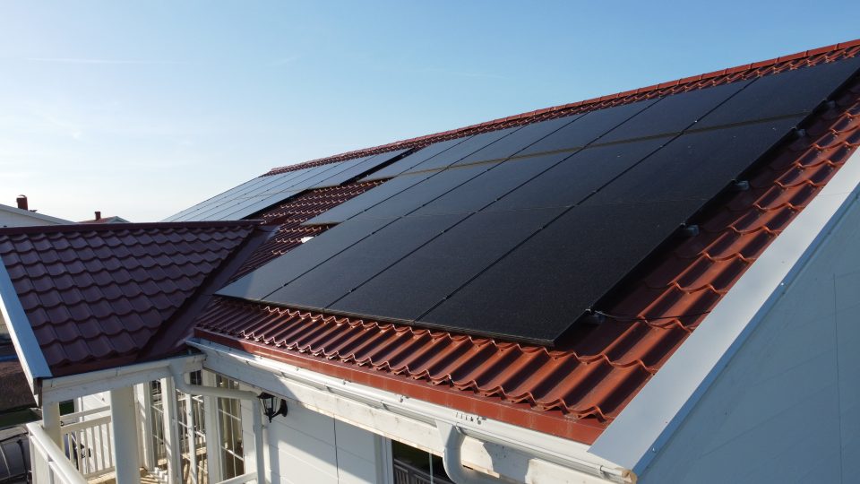 En vacker bild av solceller på ett tak mot en klar blå himmel. Solcellerna drar nytta av den strålande solen och omvandlar solenergi till elektricitet