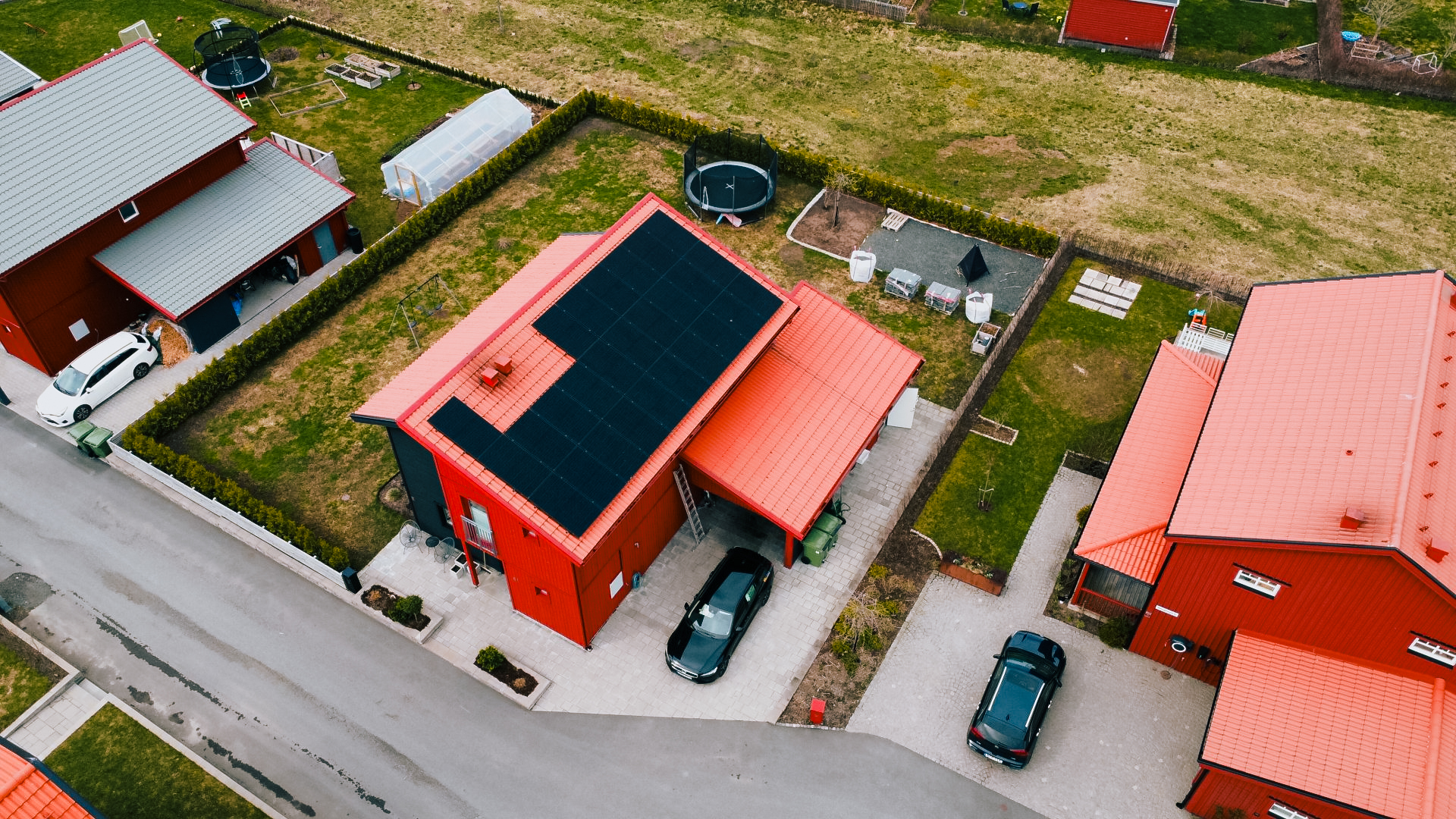Bild på ett rött hus med svarta solpaneler installerade på taket som Solifokus har varit där och installerat.