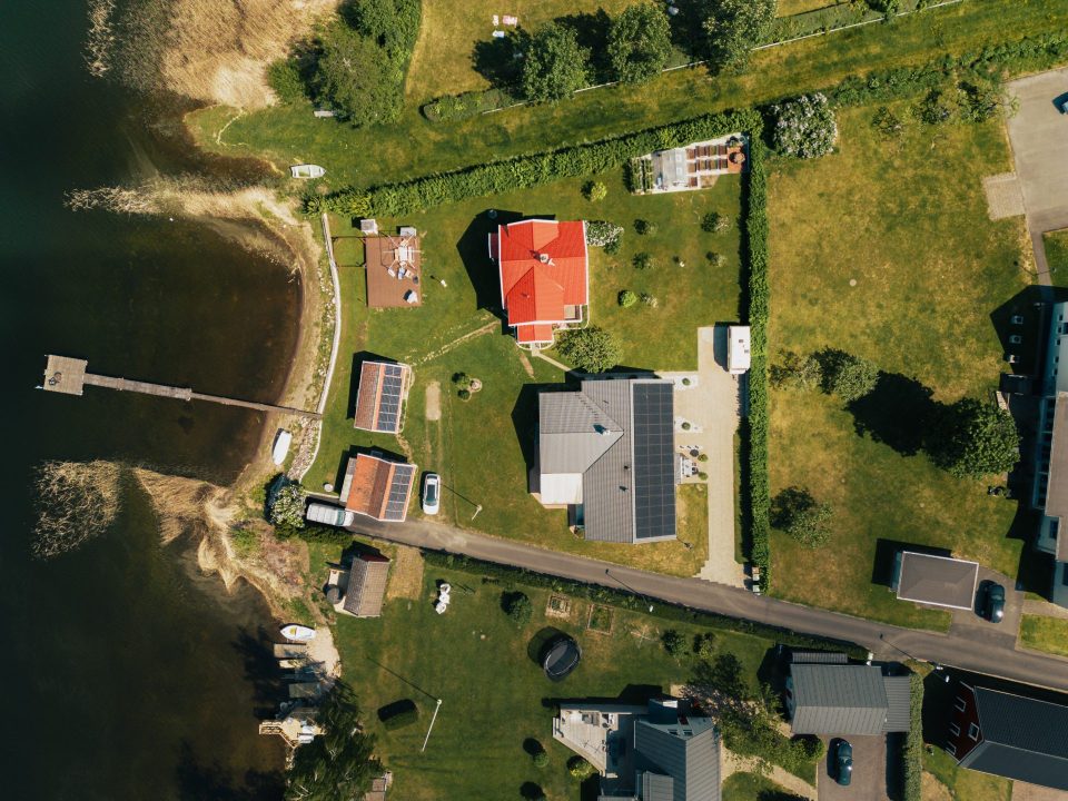 Drönarbild av ett hus med skimmerande solpaneler, i Småland, som fångar dagens solsken.